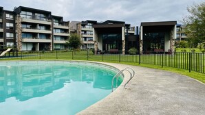 A modern building with a swimming pool, surrounded by a fence and greenery. - Buho Modern Nature Retreat - Puc n (Pucón)
