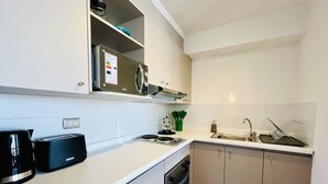 A compact kitchen with a built-in oven, a coffee machine, a sink, and a microwave. - Urbano Esperanza Plaza Yungay Laundry Pet Pool (Santiago)