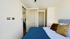 A hotel room with a bed, a wardrobe, a door leading to a bathroom, and a small kitchenette. - Urbano Esperanza Plaza Yungay Laundry Pet Pool (Santiago)