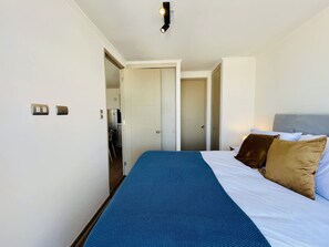 Una camera d'albergo con un letto, un armadio, una porta che dà su un bagno e un angolo cottura.