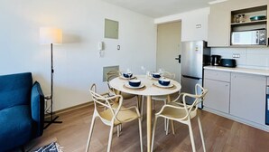 A compact kitchen with a dining table set for four, a sofa, and a standing lamp. - Urbano Esperanza Plaza Yungay Laundry Pet Pool (Santiago)