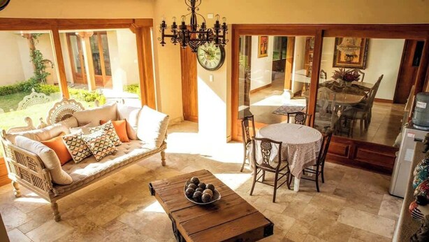 Ein gemütlicher Wohnbereich mit Sofa, Couchtisch und Esstisch, verbunden mit einer Küche und einem Garten.