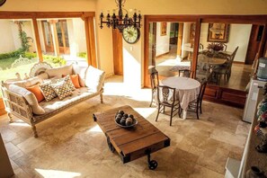 Ein gemütlicher Wohnbereich mit Sofa, Couchtisch und Esstisch, verbunden mit einer Küche und einem Garten.