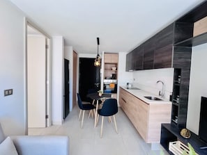 Eine moderne Küche mit Essbereich, gestaltet in Schwarzweiß, mit Holzausbau und einer schwarzen Arbeitsplatte.