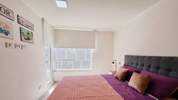 Un dormitorio con cama, ventana y adornos en la pared.