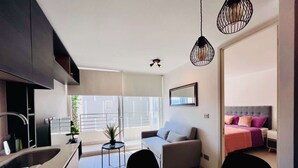 Un apartamento moderno con cocina, comedor y sala de estar. Tiene un balcón con vista a la ciudad.
