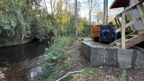 A rustic cabin with a wood-burning stove, a concrete foundation, and a wooden deck. - Caba a Roble BBQ Home Office Washer Wood Hot Tub (Loncoche)
