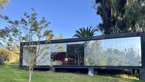 A modern glass house with a visible interior including a dining area and a kitchen. - Casa Melipill n BBQ Jacuzzi Mini-pool Pet Wifi (Melipilla)