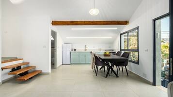 A modern kitchen with a dining area, wooden beams, and a large window.