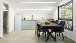 Eine moderne Küche mit Essbereich, ausgestattet mit einem Holzbalken an der Decke, einem großen Fenster und Blick ins Grüne.