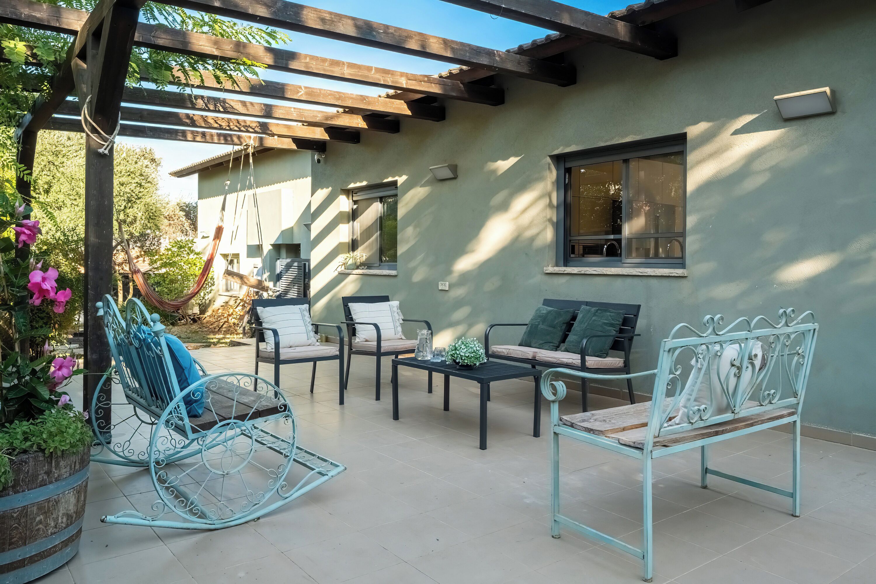 A patio with outdoor furniture, including a rocking chair, sofas, and a table.