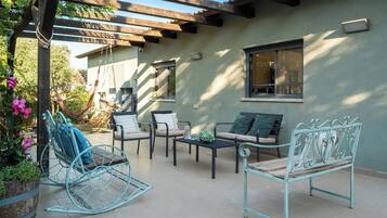 A patio with outdoor furniture, including a rocking chair, sofas, and a table.