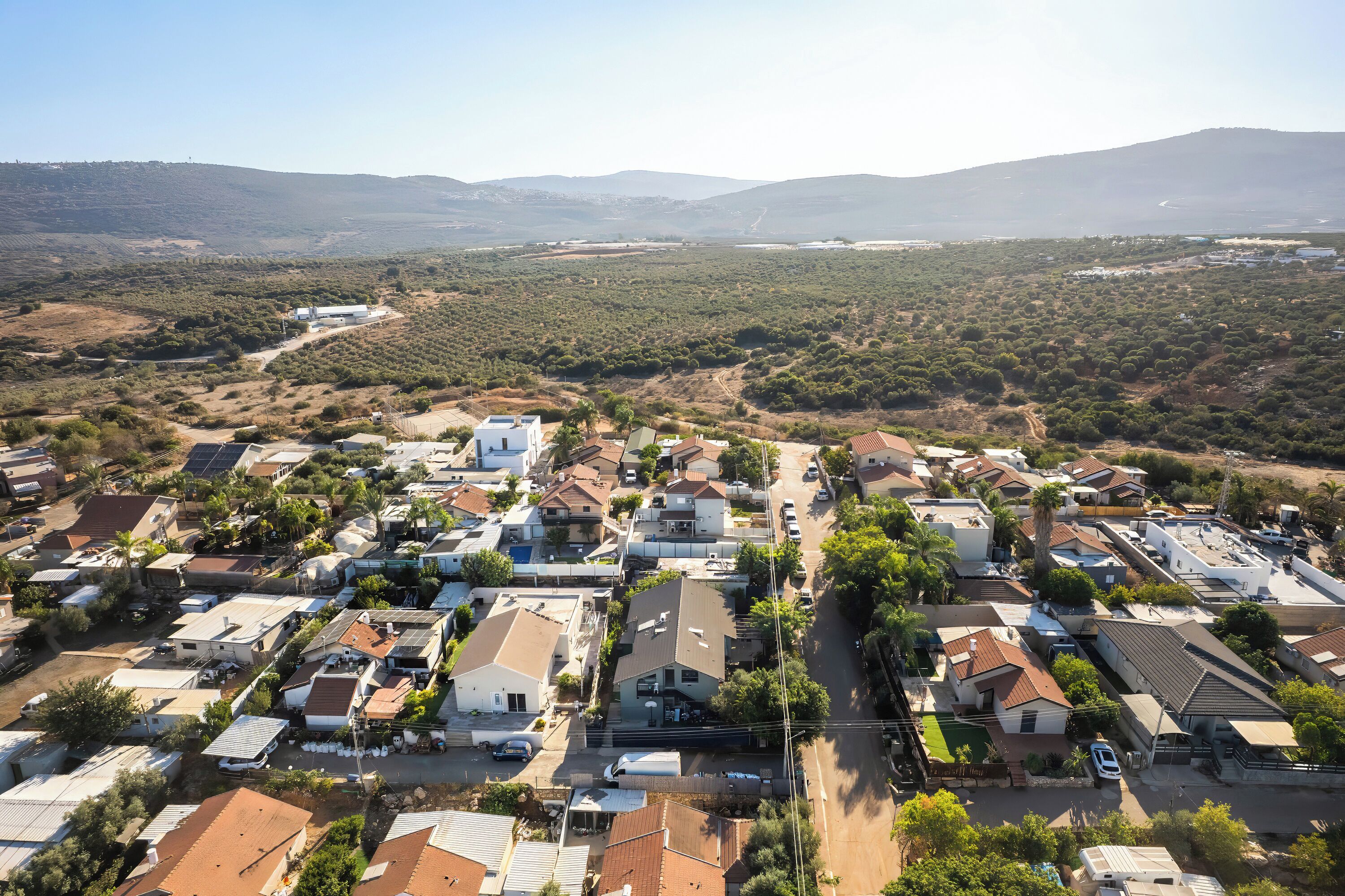 Vista aérea de una zona residencial con casas, carreteras y un paisaje montañoso al fondo.