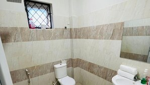 A small bathroom with a toilet, a sink, and a shower. - Nyali Luxe 2BR • Beach - Parking - Peaceful, Safe (Mombasa)