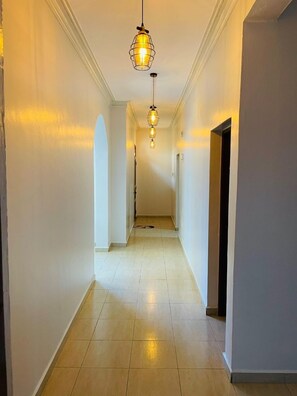 A hallway with three pendant lights, white walls, and a tiled floor. - Nyali Luxe 2BR • Beach - Parking - Peaceful, Safe (Mombasa)