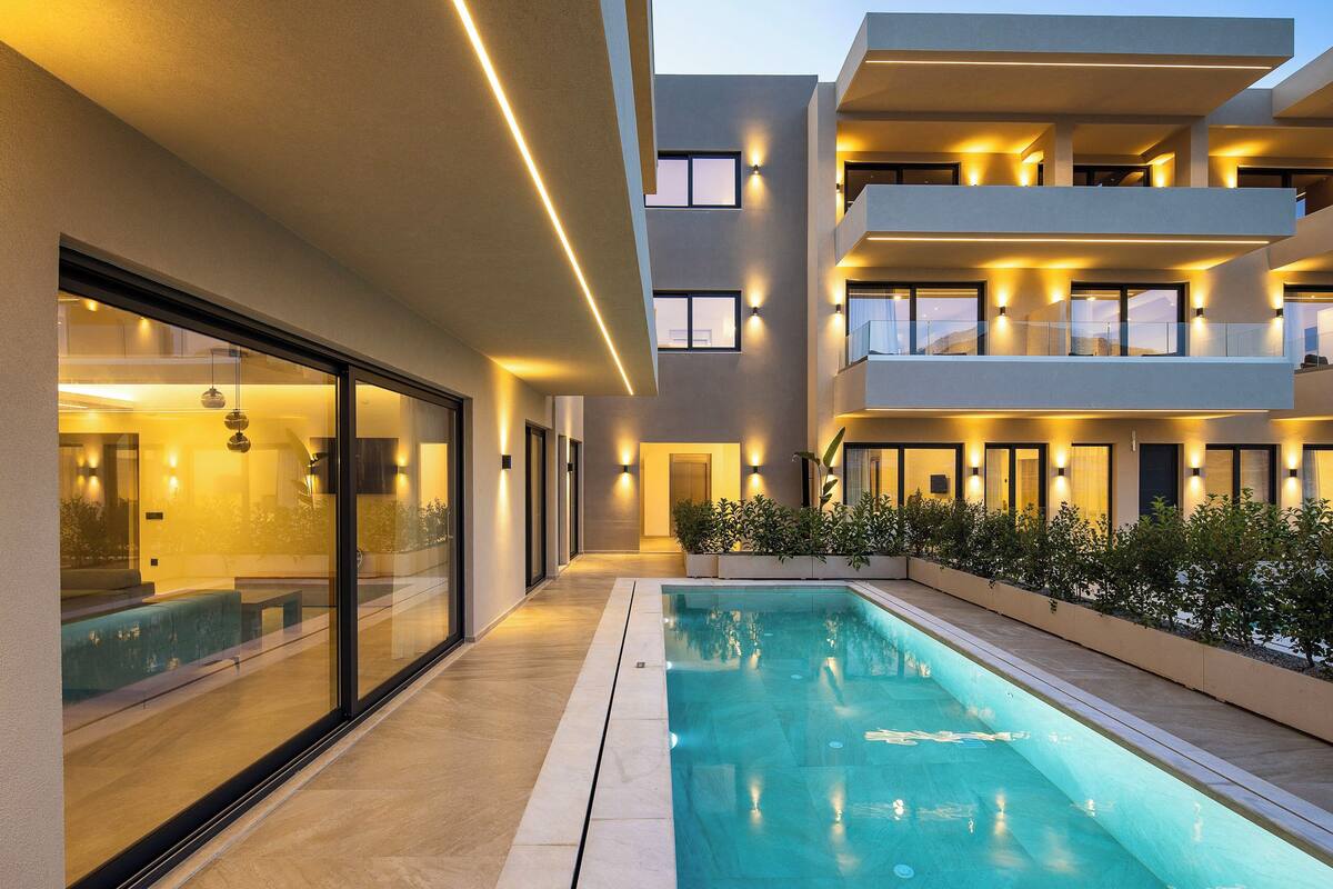A modern building with a swimming pool, large windows, and outdoor lighting.