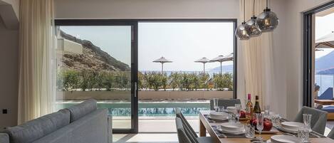 A modern dining area with a pool view, a sofa, and a table set for dining.