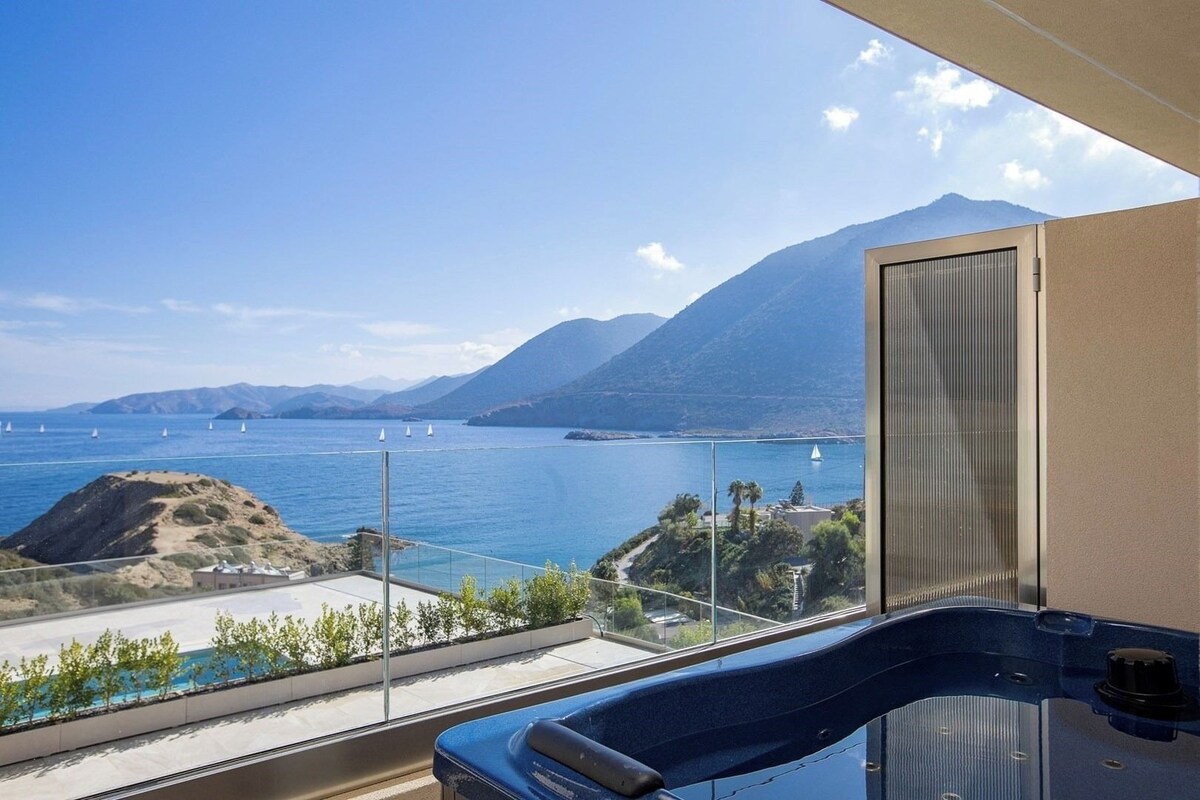 A balcony with a view of the sea, mountains, and a distant island.