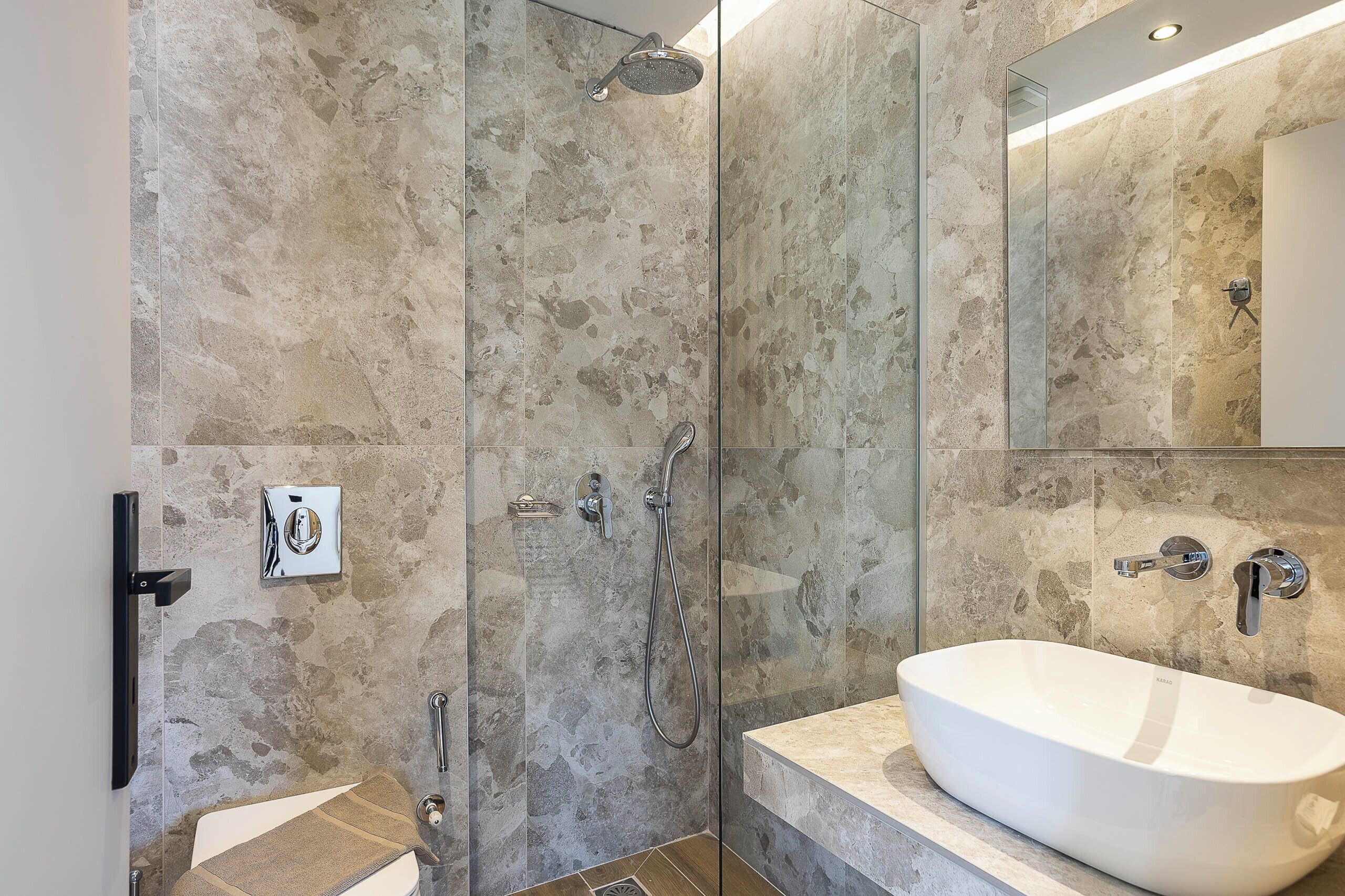 Une salle de bain moderne avec une baignoire sur pieds, une douche à parois de verre et un mur en marbre.