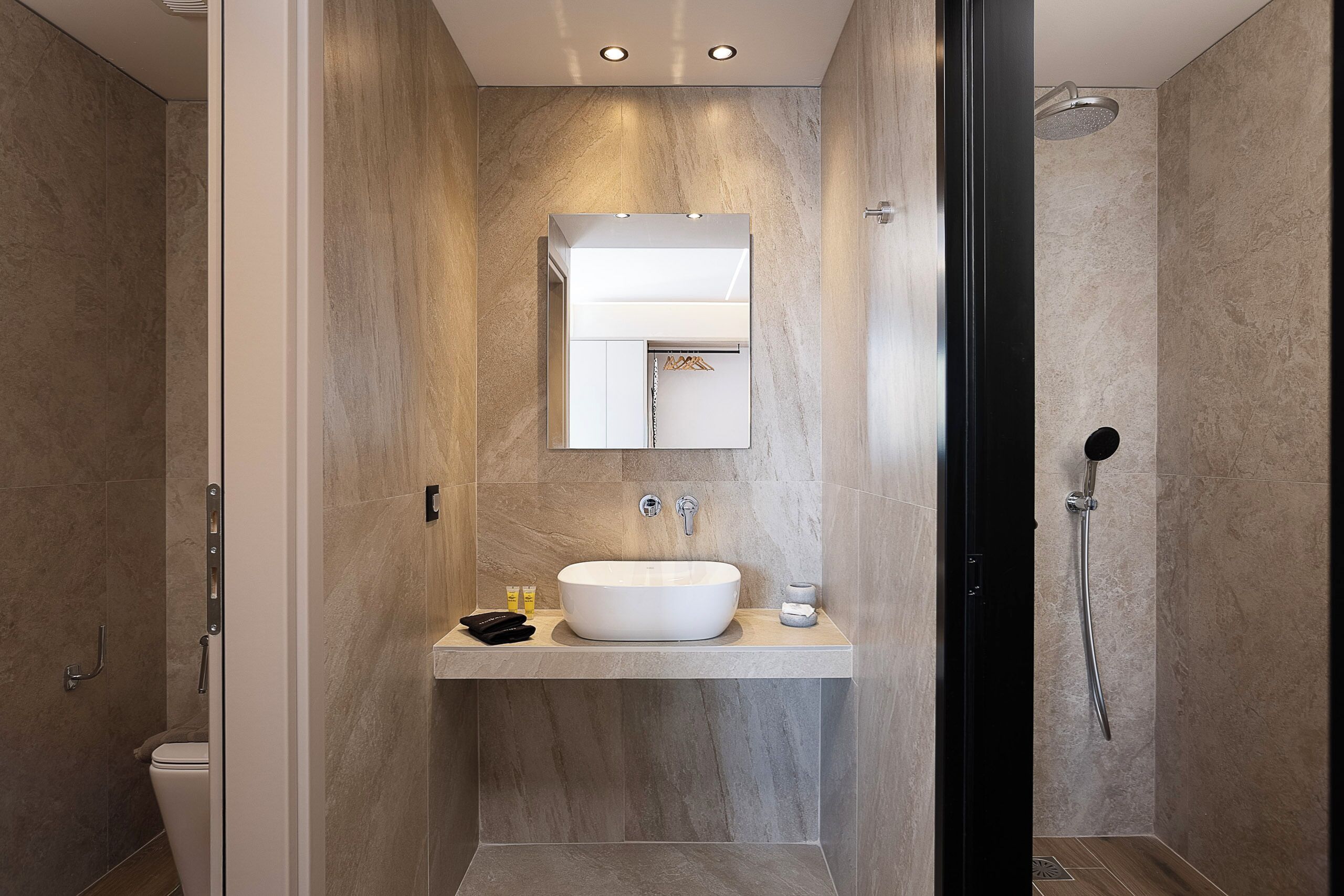A modern bathroom with a large sink, mirror, and shower.