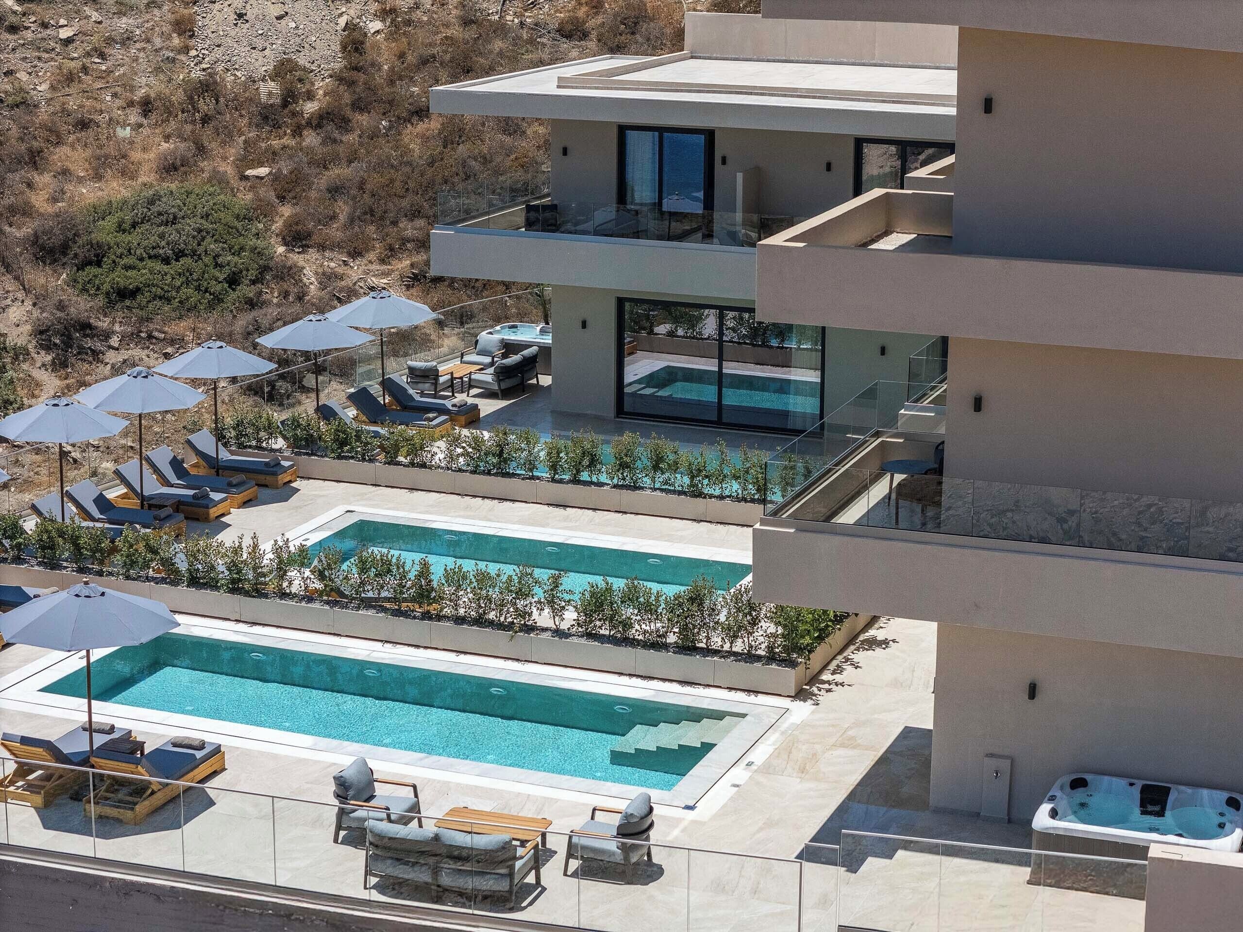 A modern multi-story building with a rooftop pool area, including sun loungers and umbrellas.