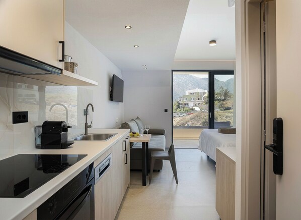 Una cocina compacta con electrodomésticos modernos, un comedor con mesa y sillas, y un dormitorio con cama y ventana.