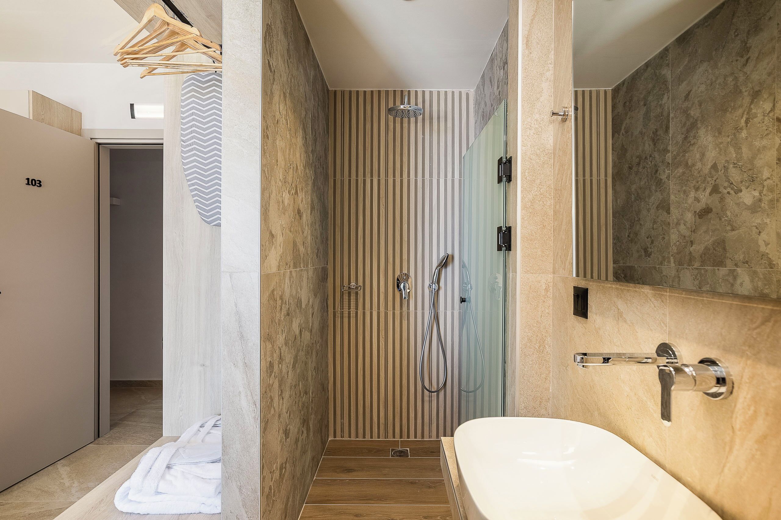 A modern bathroom with a large bathtub, a shower with a handheld showerhead, and a vanity with a mirror.