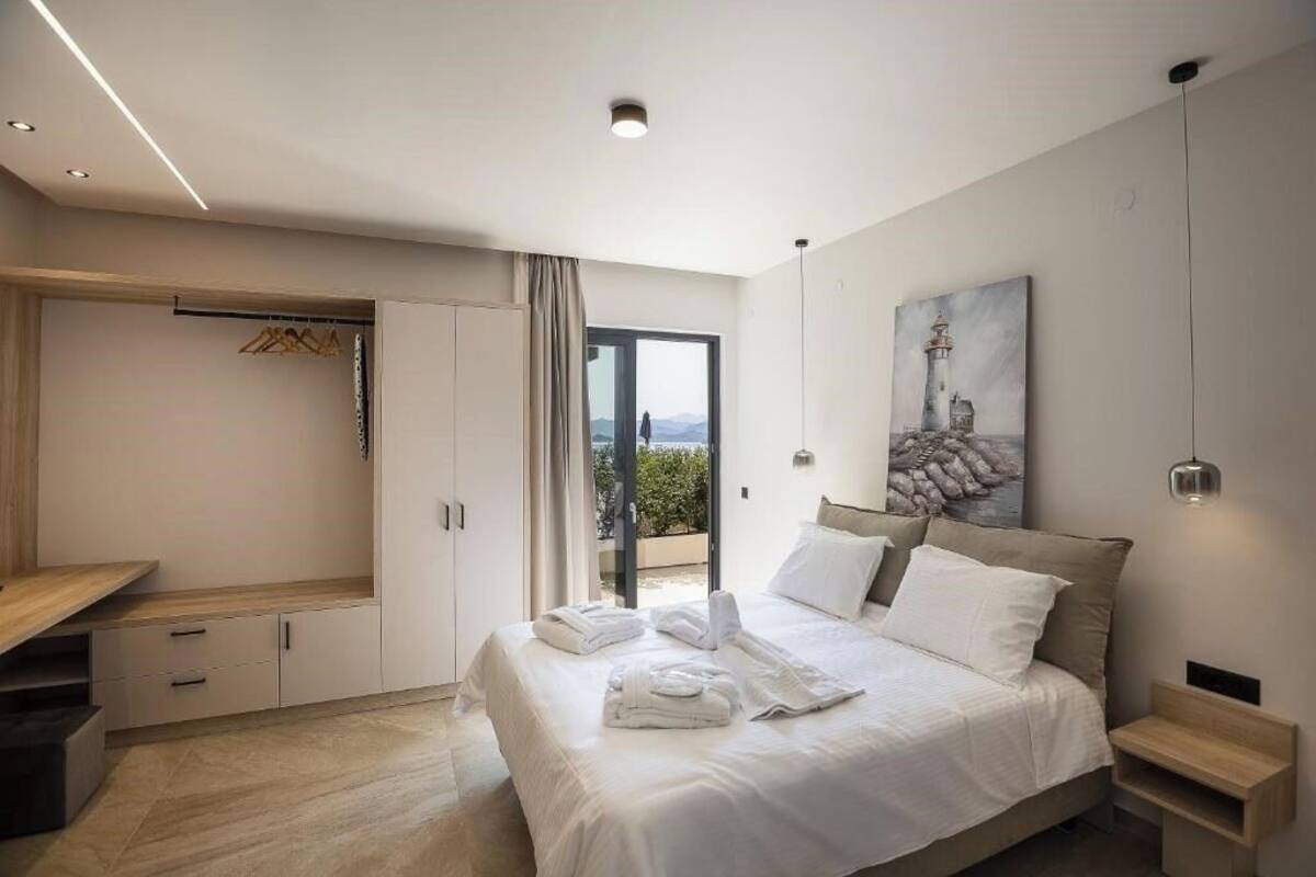 A modern bedroom with a bed, a wardrobe, a desk, and a painting.