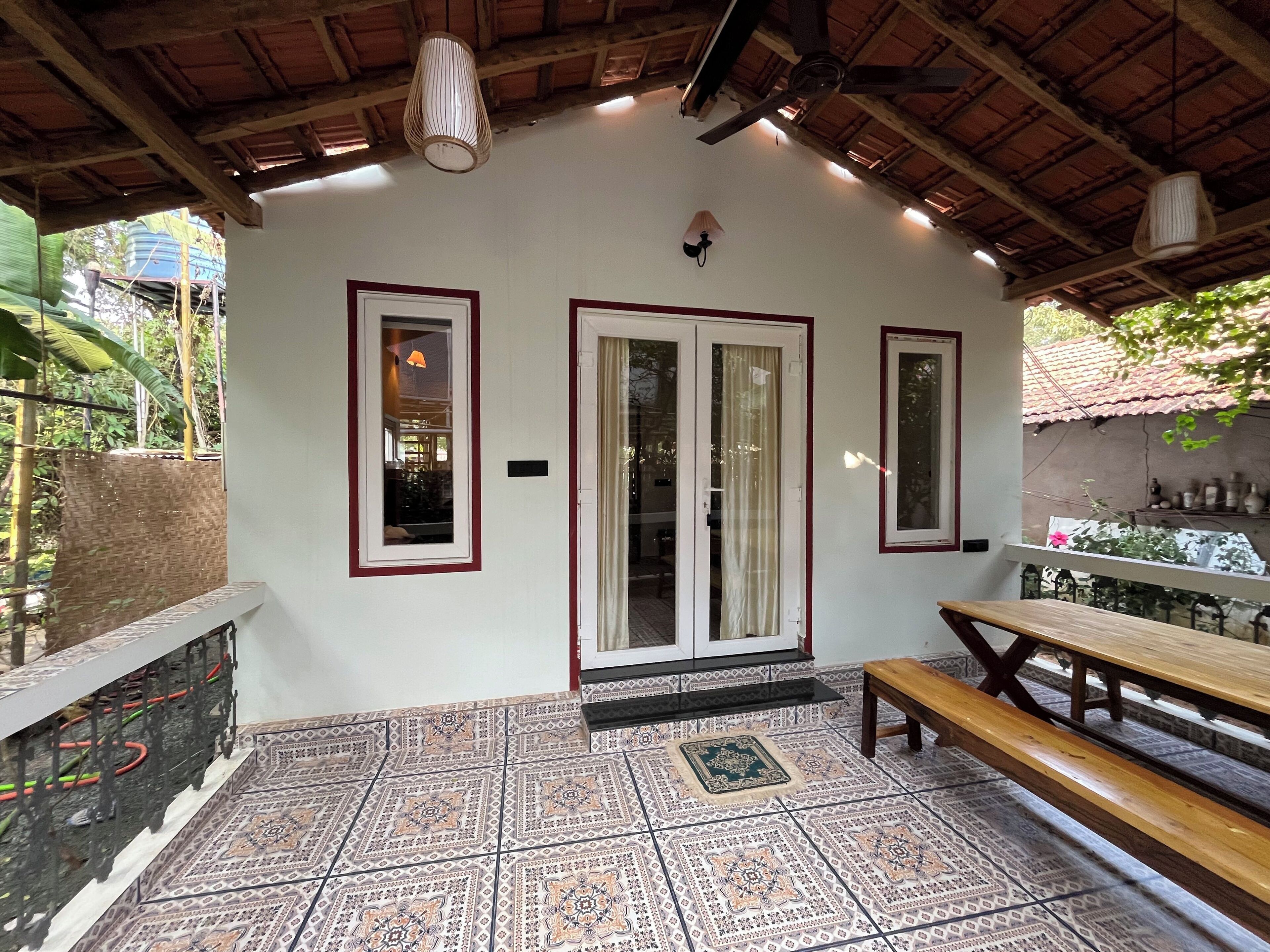 A covered patio with patterned tiles, a wooden bench, and a table.