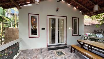 A covered patio with patterned tiles, a wooden bench, and a table.