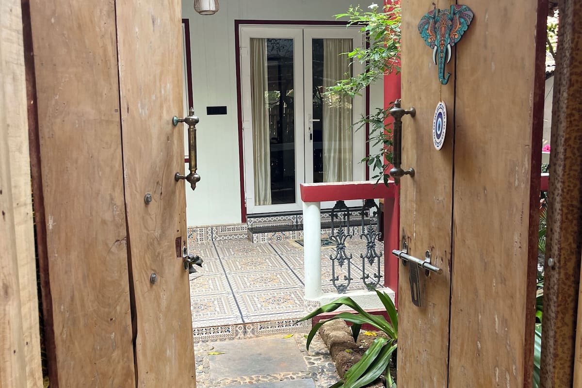 A wooden door leading to a covered patio with a tiled floor, a ceiling fan, and a decorative elephant ornament.