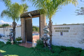 A building entrance with a sign reading 'CORTIJNO PALOMO,' a brick wall, and two statues of a bull and a goose. - Country House 'Cortijo Palomo' with Private Pool and Mountain Views (Málaga)
