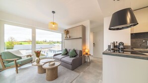 A modern living room with a sofa, coffee table, and a view of the outdoors. - Halternative Muscari (Luxembourg City)