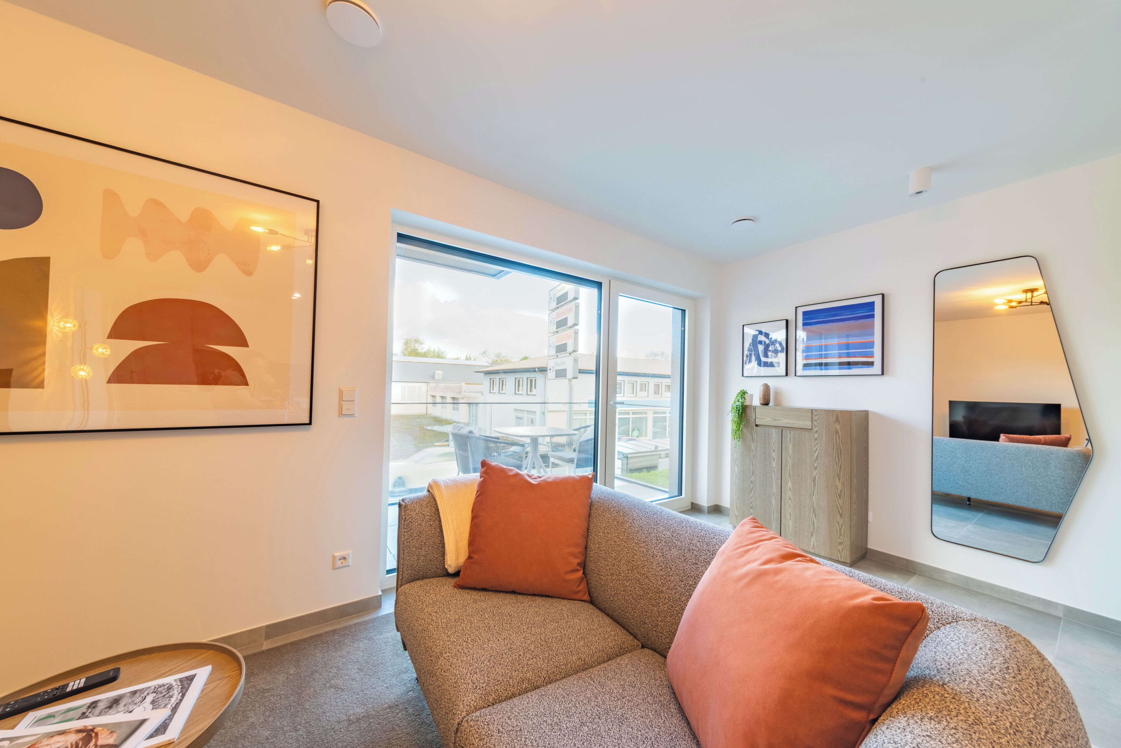 A modern living room with a sofa, a coffee table, and a large window offering a view of the city.