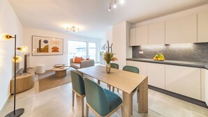 A modern kitchen with white cabinets and a black countertop. - Halternative Muscari (Luxembourg City)