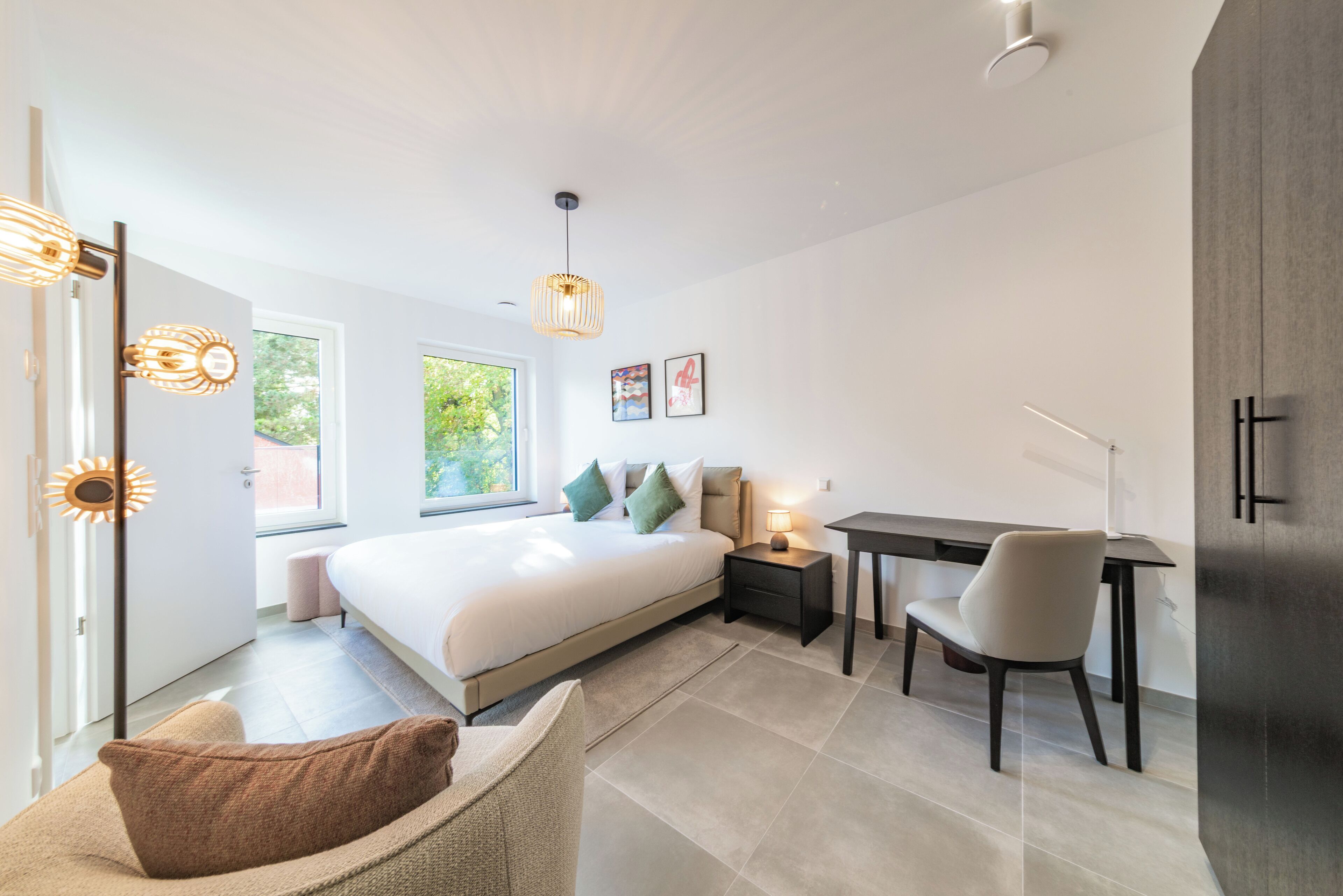 A modern bedroom with a large bed, bedside tables, a desk, and a chair.