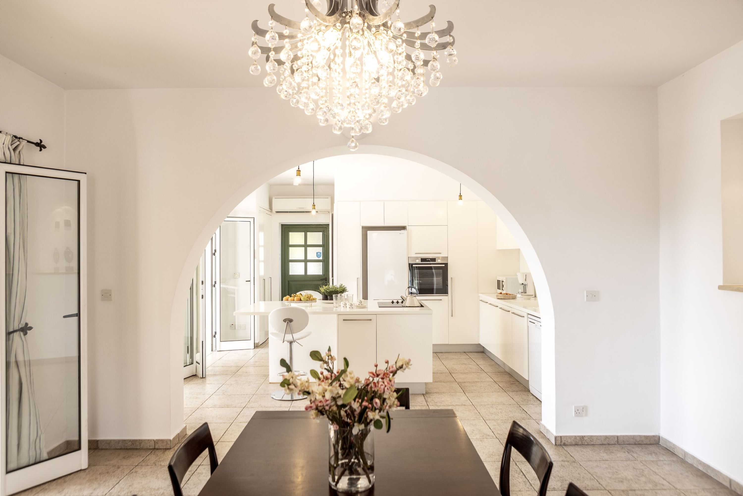 A modern kitchen with white cabinets, a central island, and a chandelier.