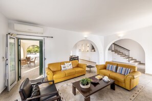 A modern living room with two yellow sofas, a coffee table, and a staircase. - Rhodia Villa in Steni (Steni)