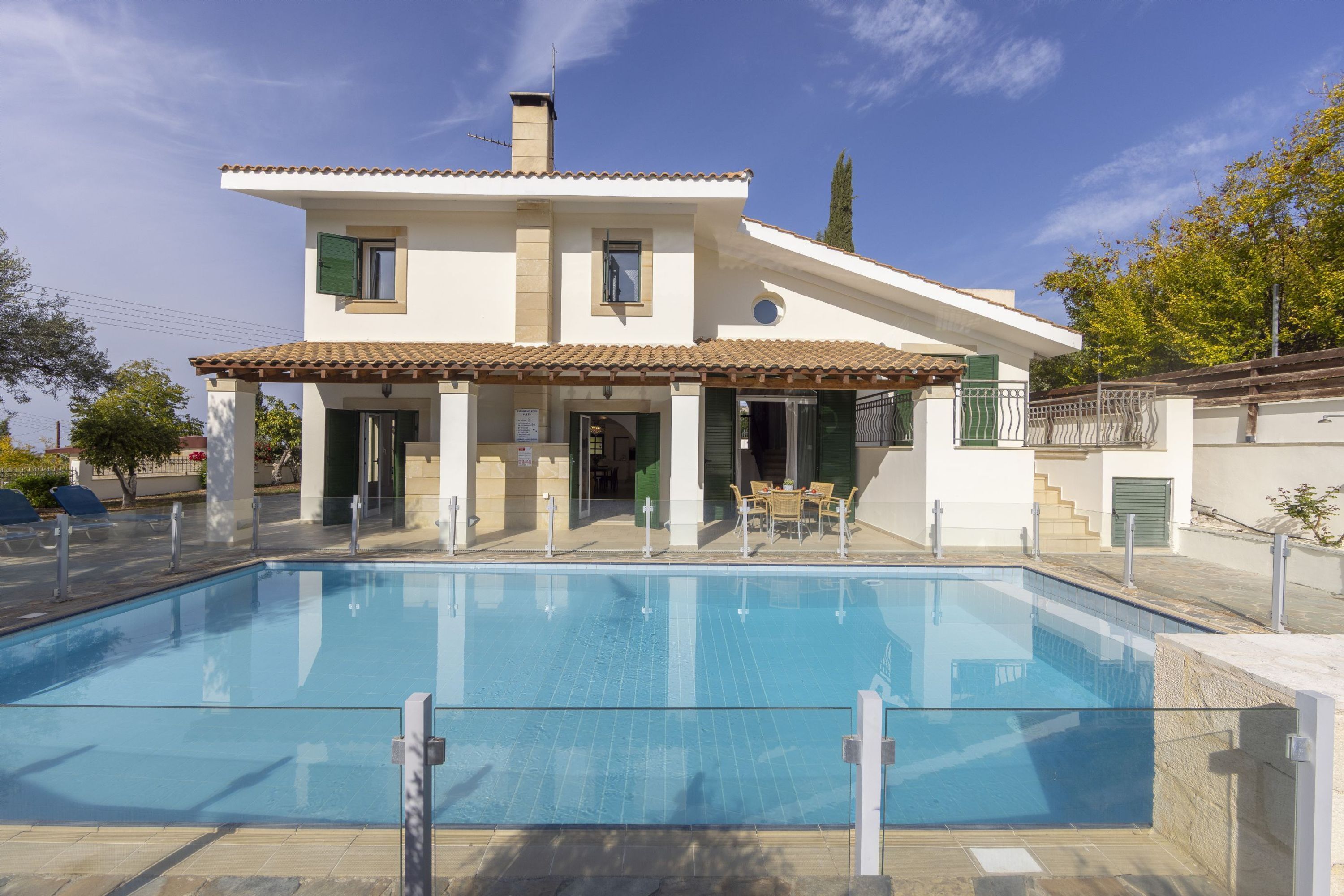 A two-story house with a swimming pool, outdoor seating, and a staircase leading to the upper floor.