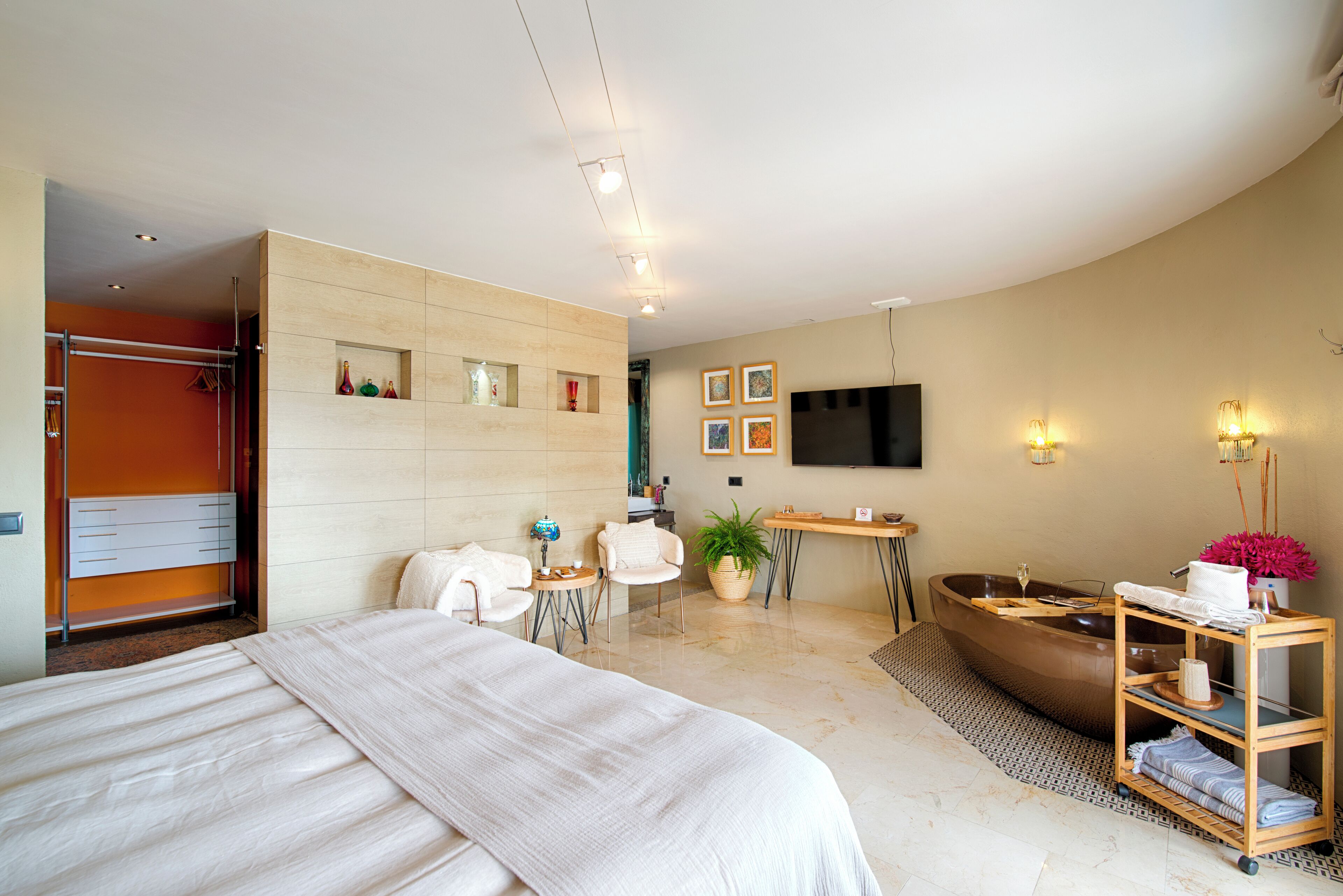 Una habitación de hotel moderna con una cama grande, un área de estar con sillas, una bañera, un escritorio y un televisor.