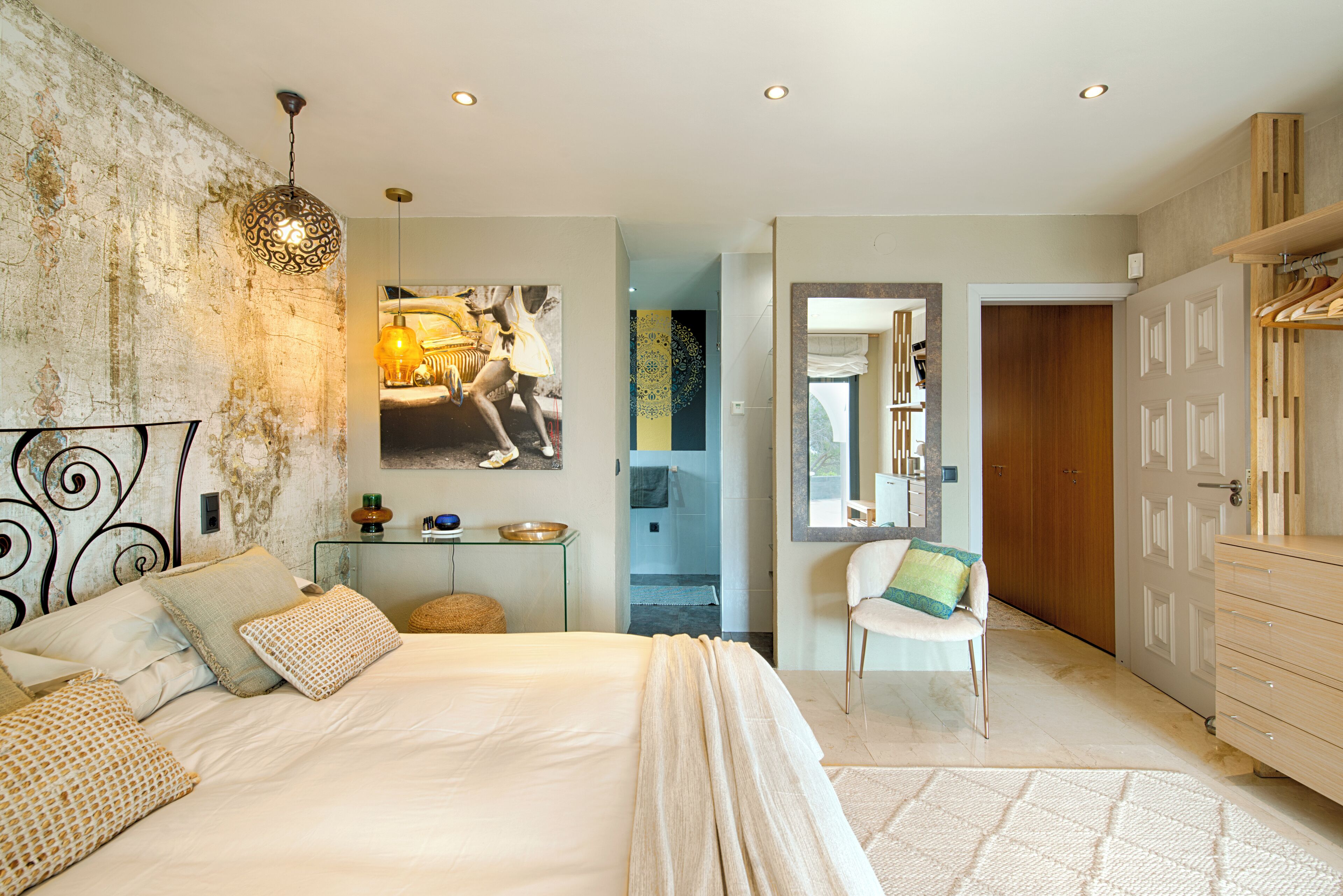 Een slaapkamer met een groot bed, een nachtkastje, een stoel, een kledingkast en een wand met een structuur.