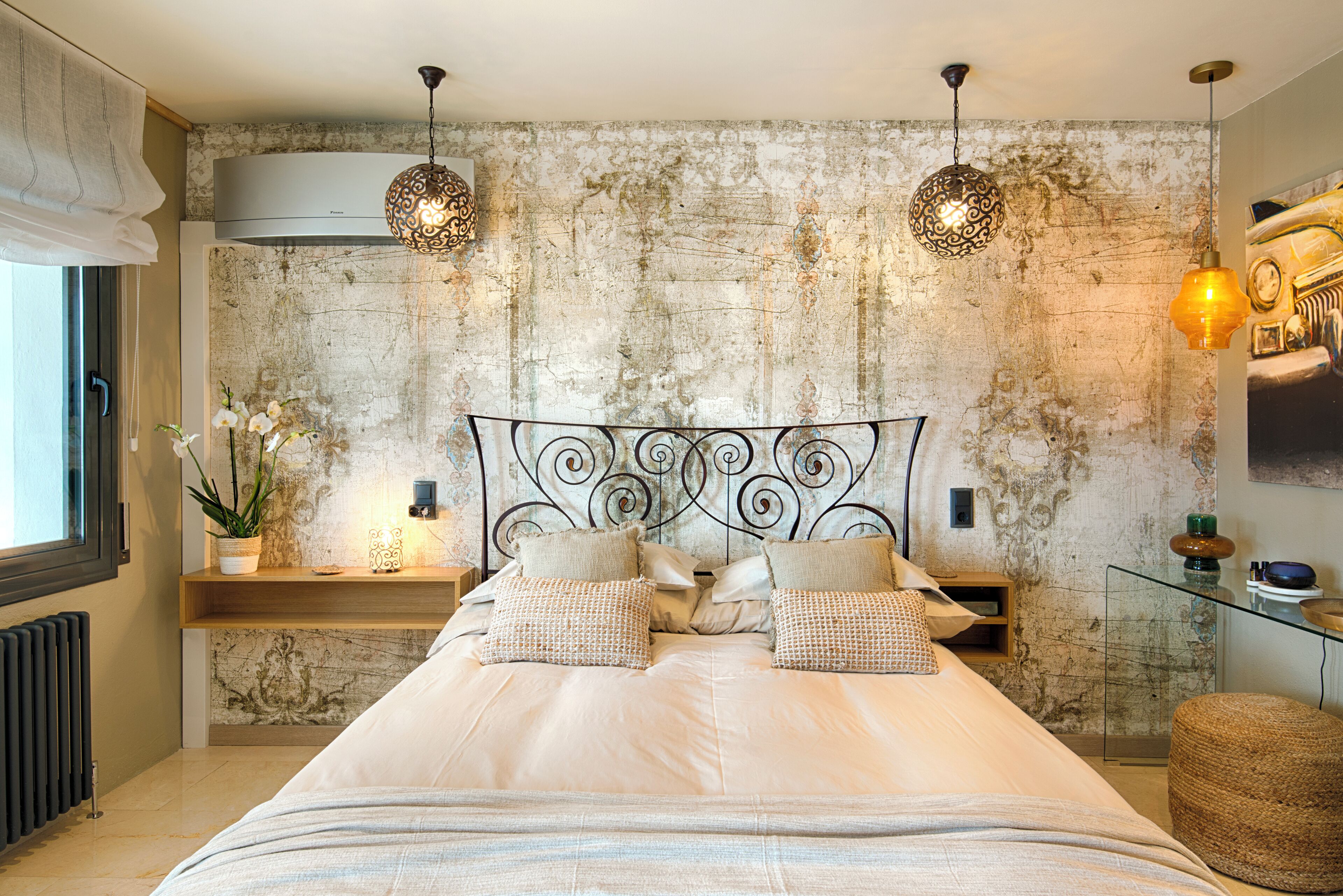 A modern bedroom with a large bed, two pendant lights, a radiator, and a window with curtains.