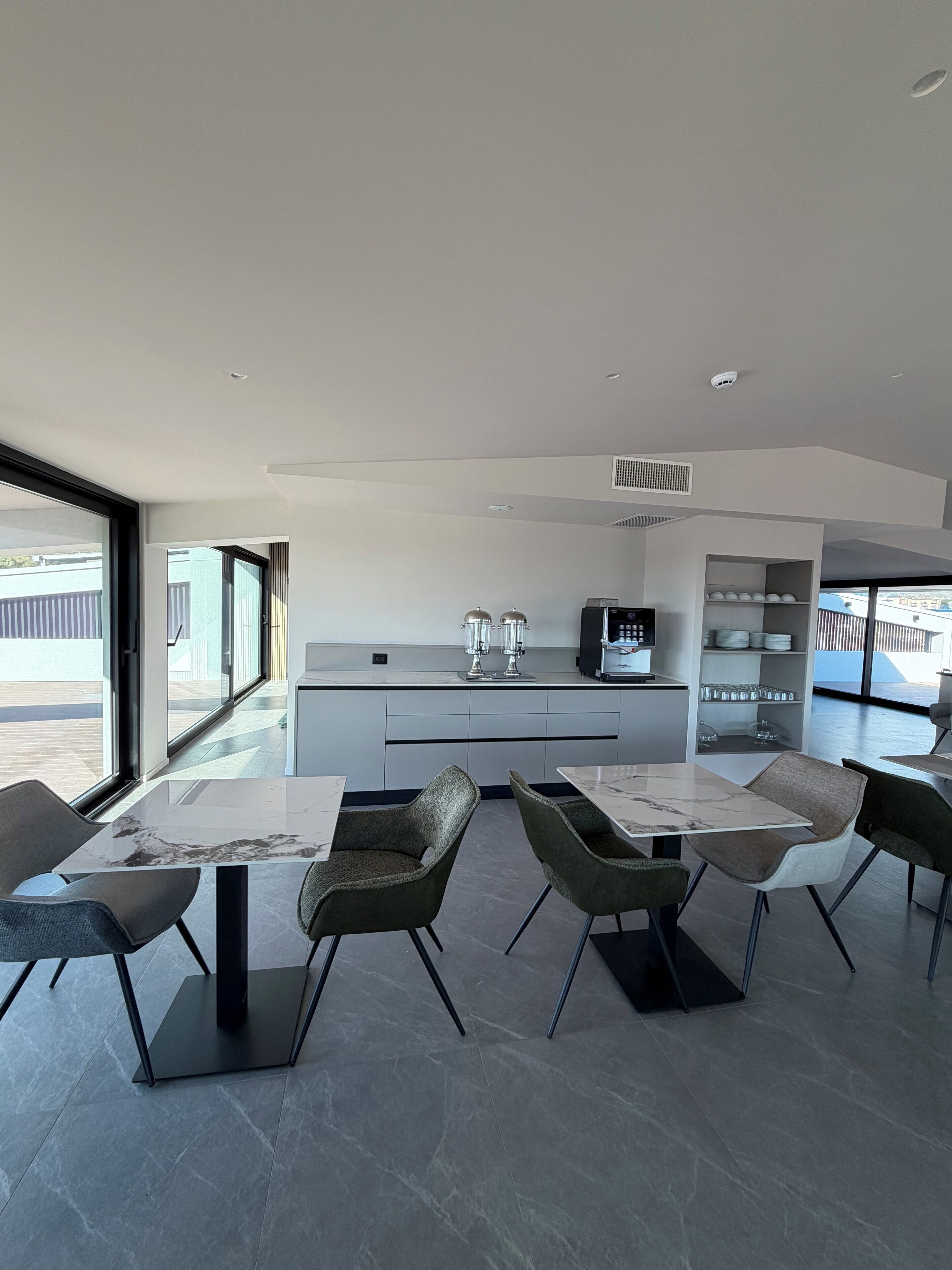 A modern kitchen with a central island, built-in appliances, and a large window offering a view of the outdoors.