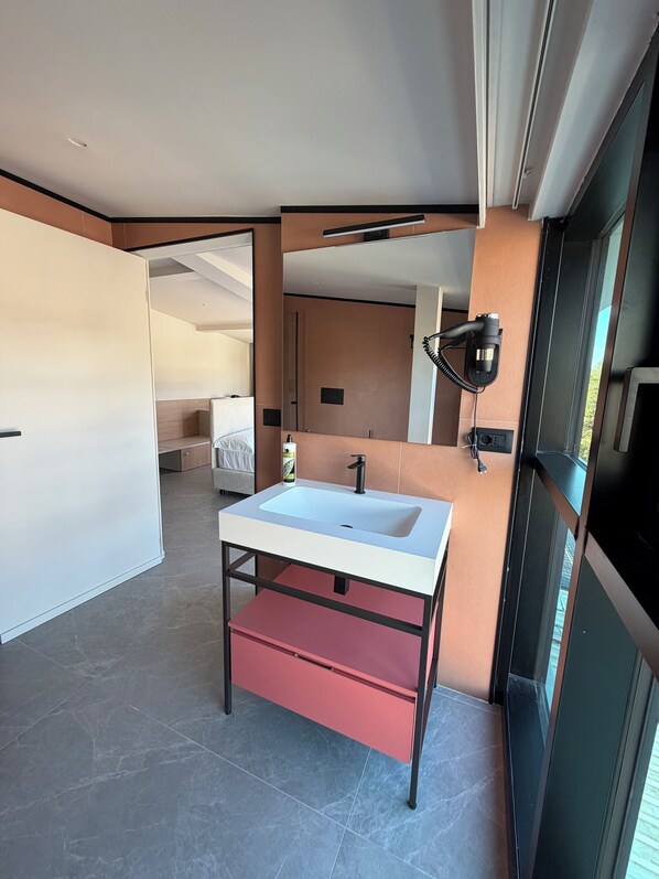 A modern bathroom with a white sink, a red storage drawer, and a large mirror. - Lamal Hotel (Naples)