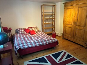 Een slaapkamer met een bed, een kledingkast, een klein tafeltje en een wereldbol.