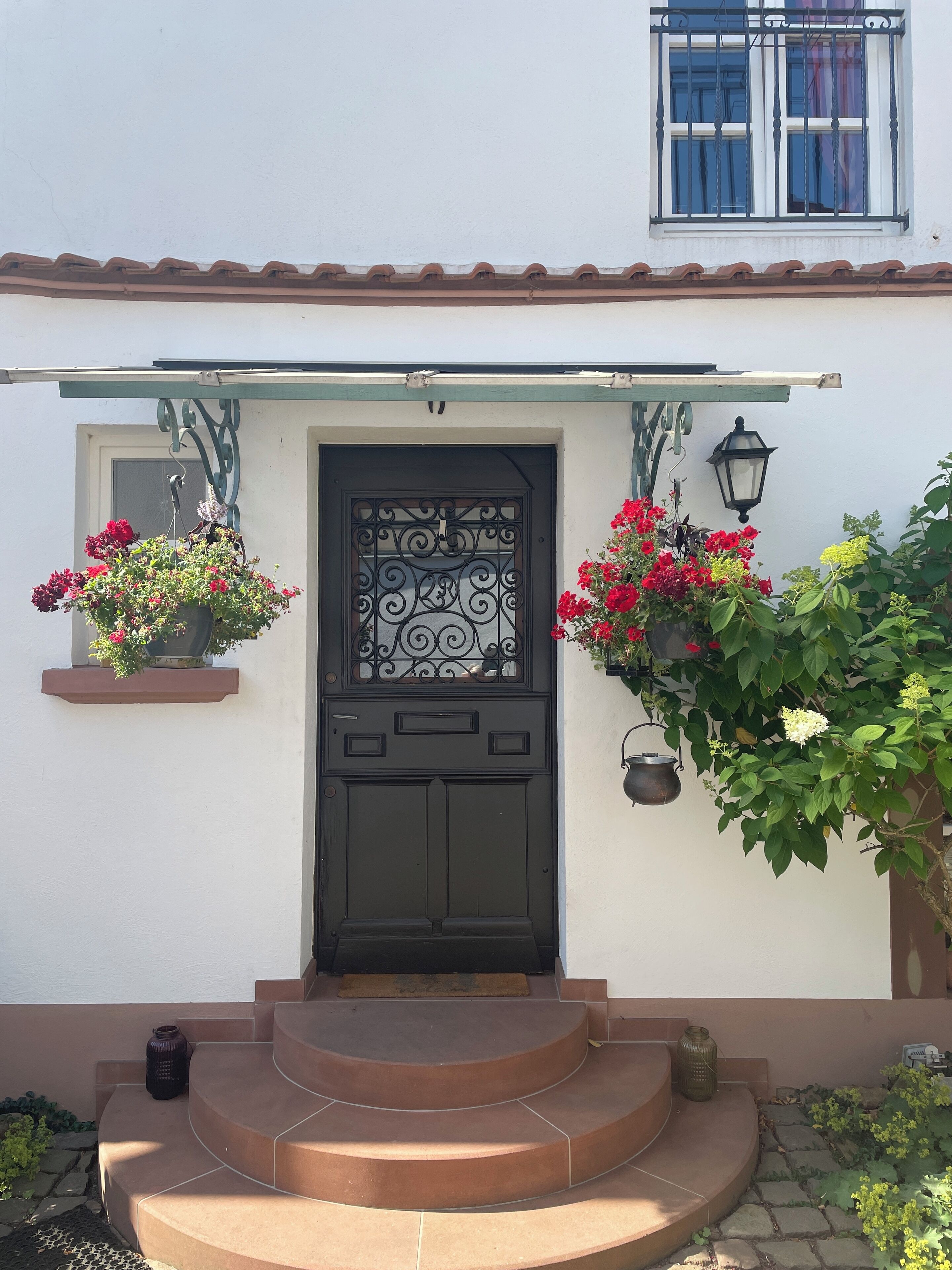 A house with a black door, a small porch with steps, and hanging flower baskets.