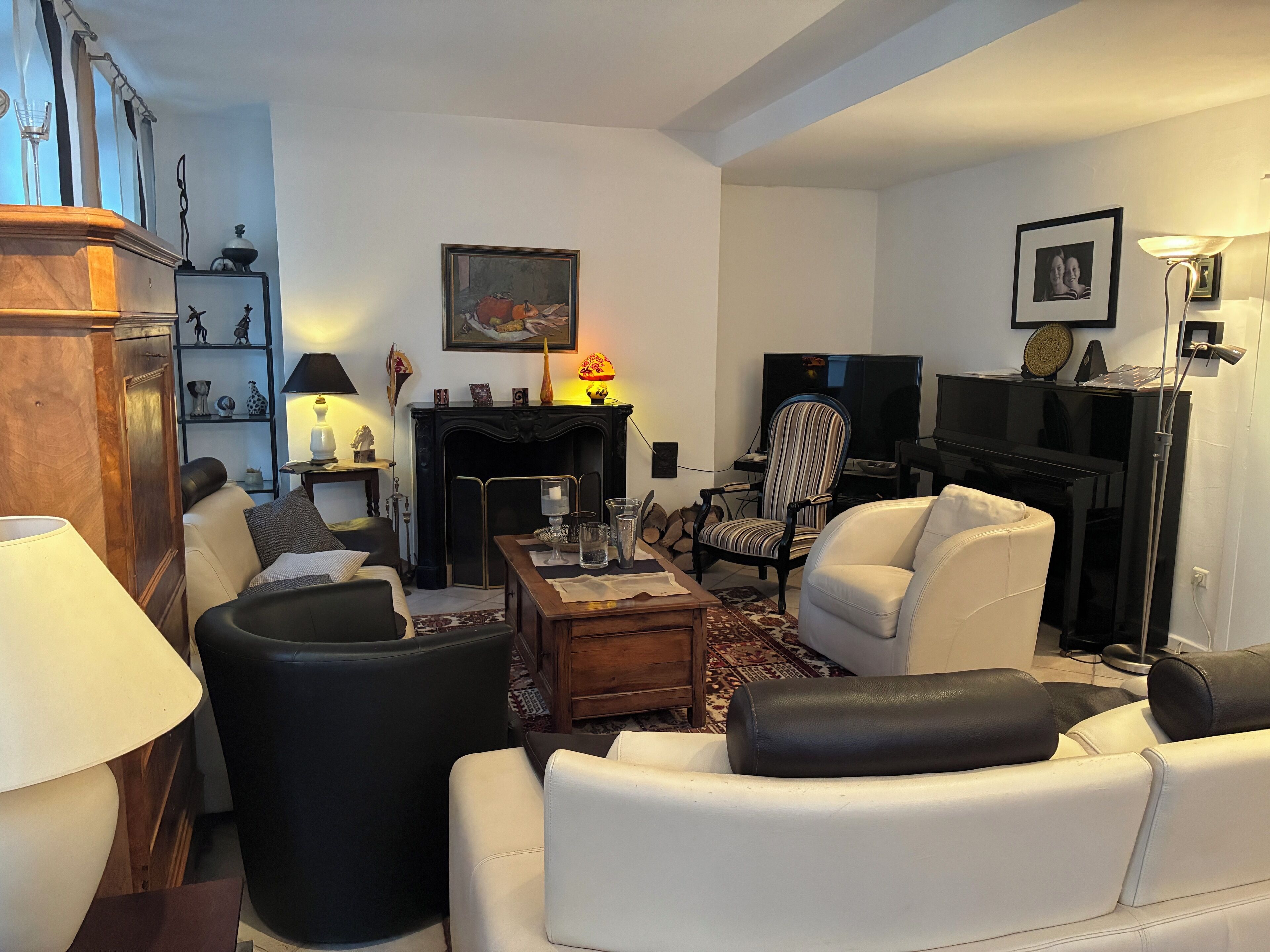 Un salon avec une cheminée, un téléviseur et un piano.