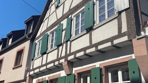 A traditional half-timbered building with multiple windows and green shutters. - Large, comfortable half-timbered house with courtyard in the heart of Wissembourg (Wissembourg)