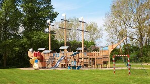 Ein Spielplatz mit Rutschen, Klettergerüsten und einem Fußballtor.