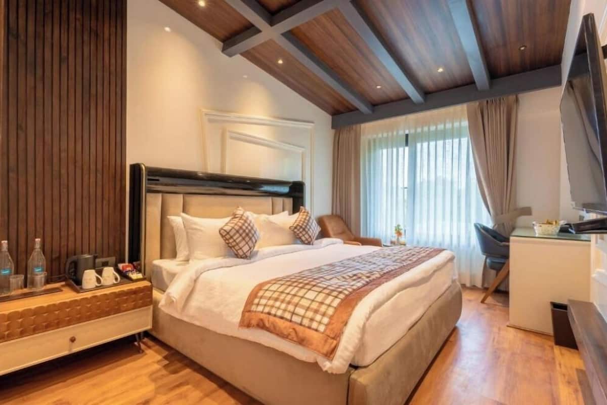 A modern hotel room with a large bed, a desk, and a TV.